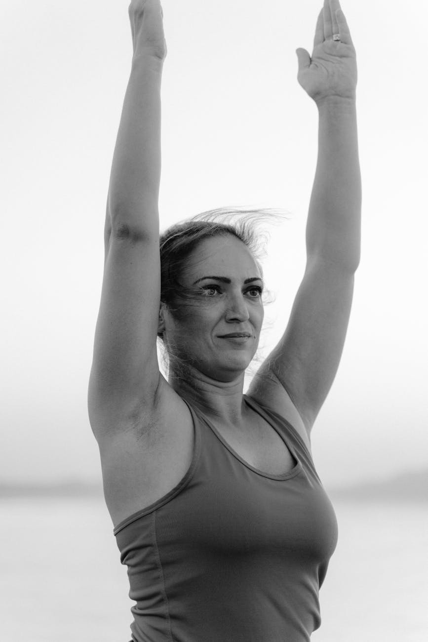 Woman performing a graceful stretch outdoors near water.